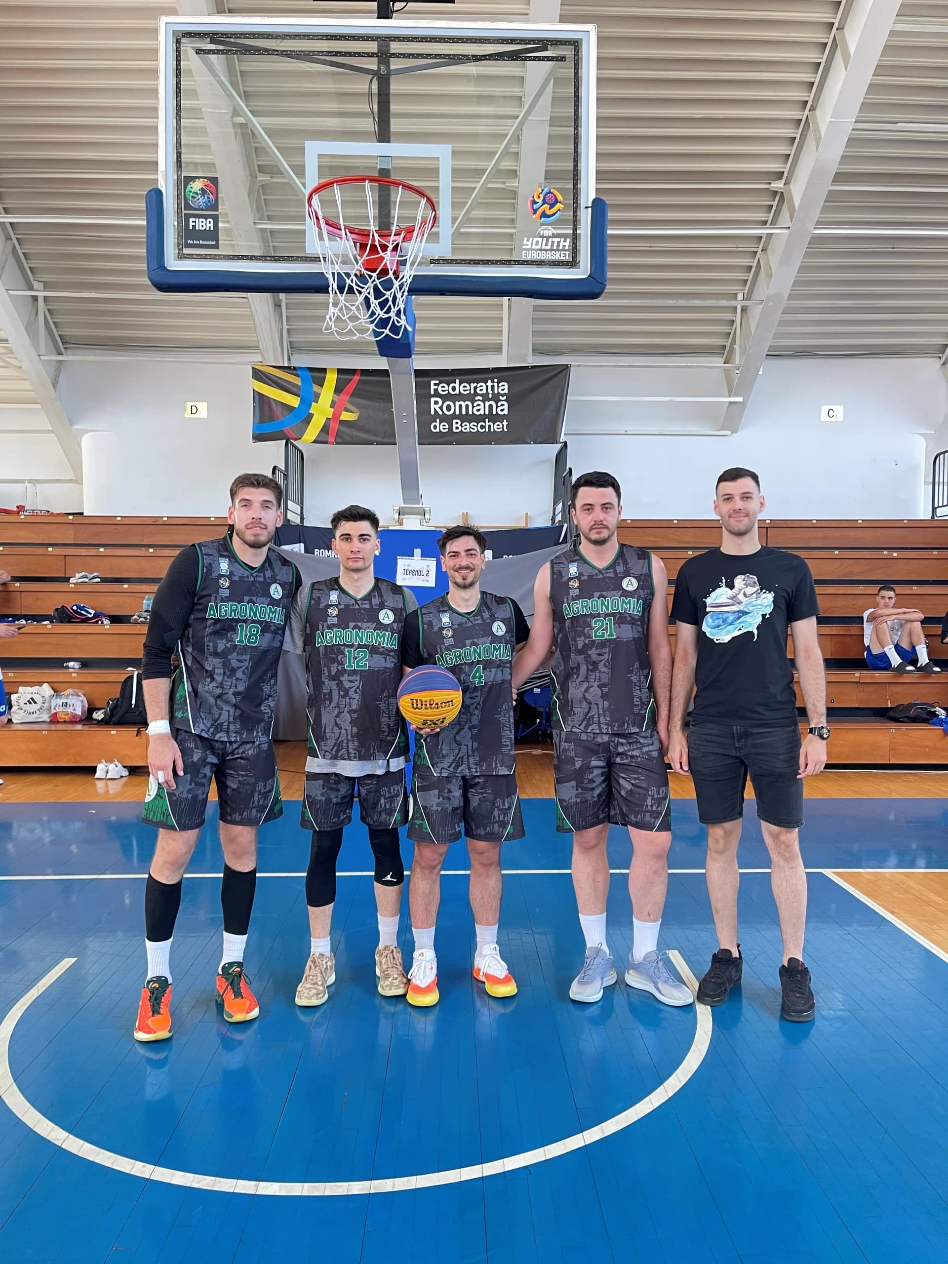 Echipa masculină de 3x3 aliniată sub panou, în fața tribunelor goale