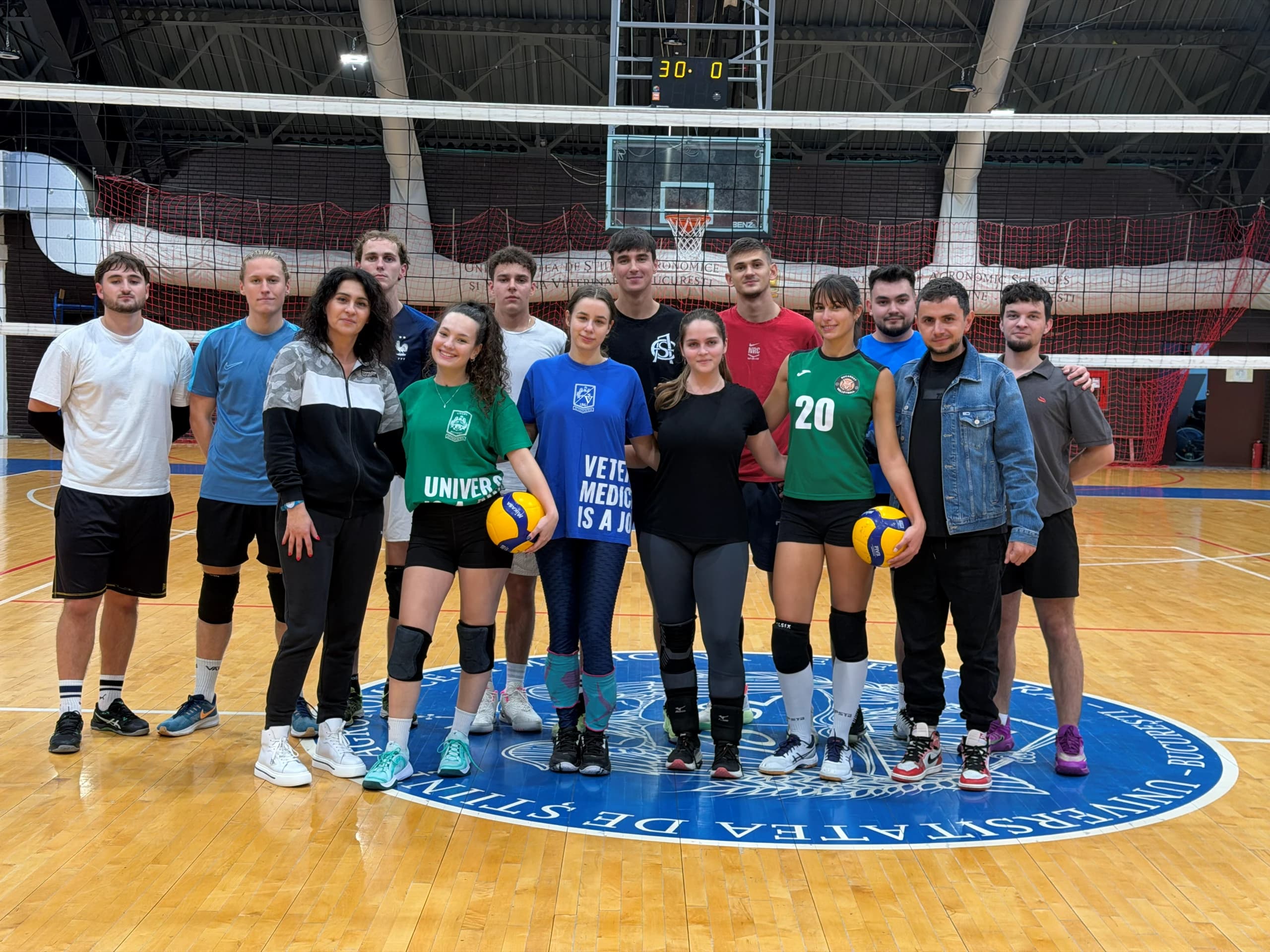 Grupul de jucători și antrenori la fileu, în sala din campus