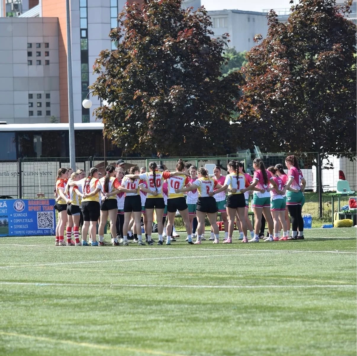 Jucătoarele de rugby, adunate în cerc la mijlocul terenului înaintea meciului