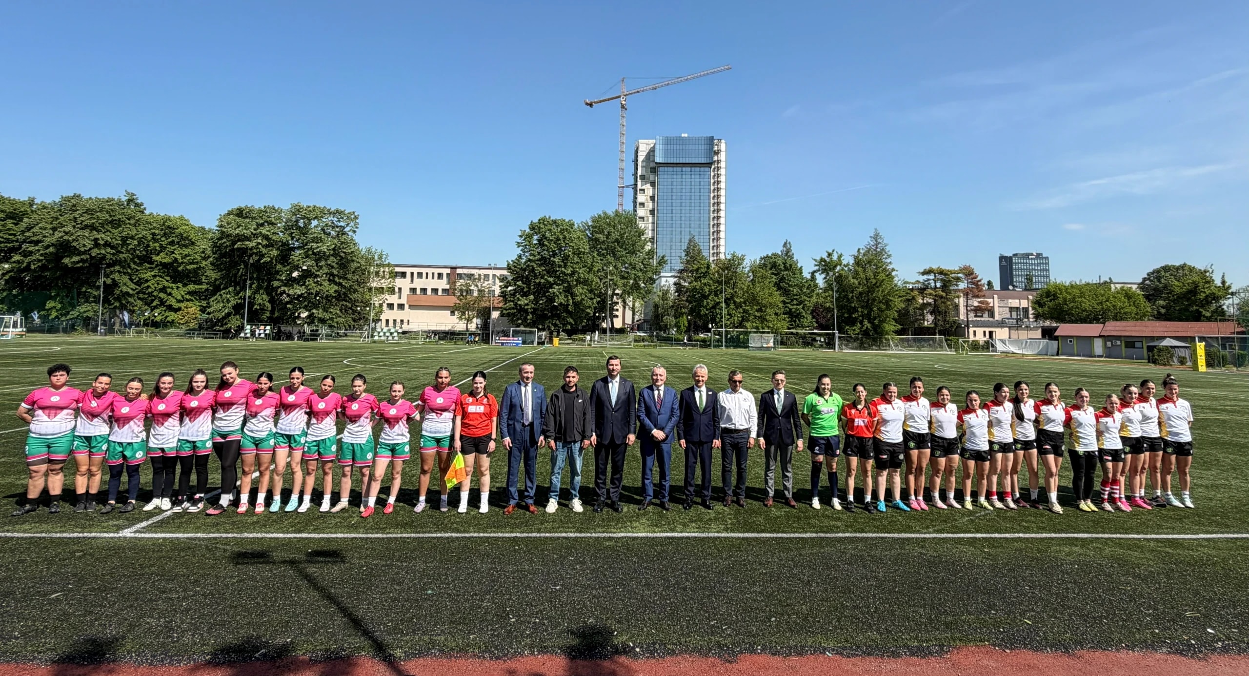 Jucătoarele de rugby, aliniate la mijlocul terenului de sport din campus