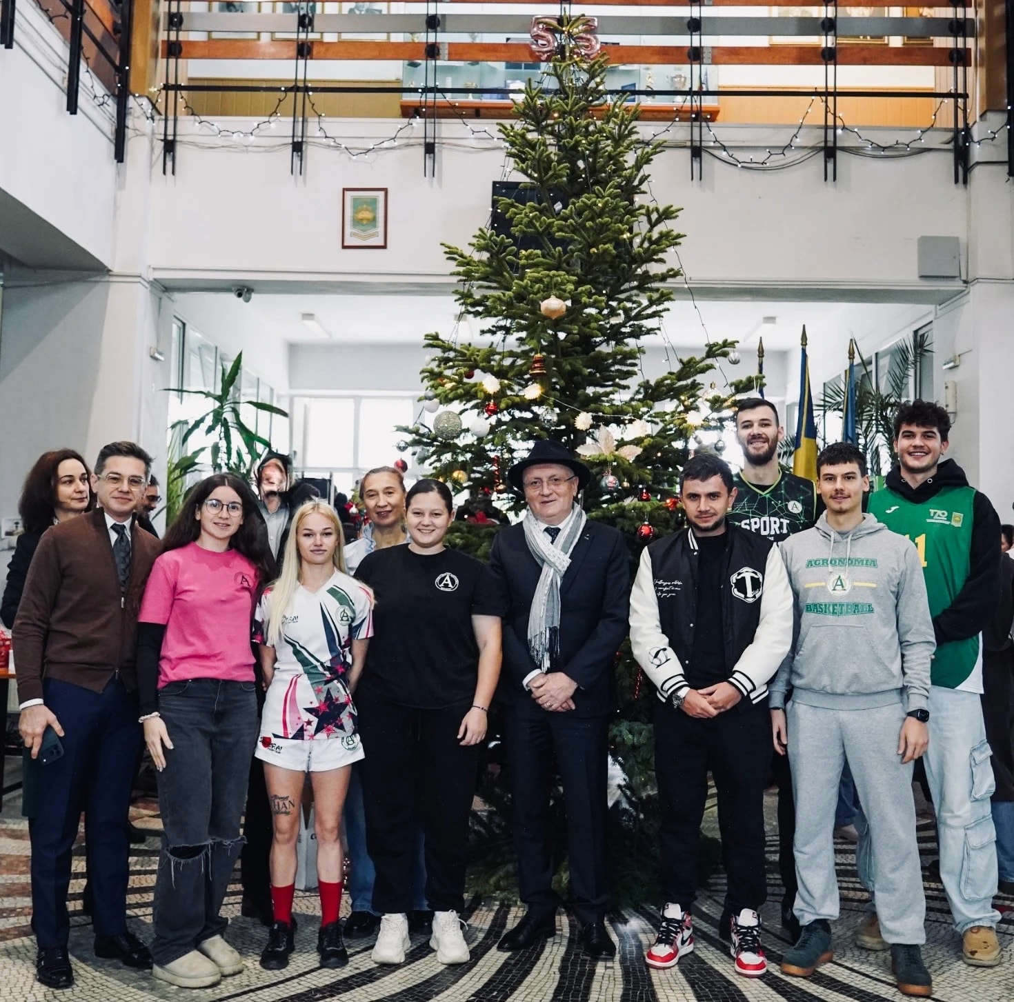 Sportivi, studenți și cadre universitare lângă bradul din holul universității