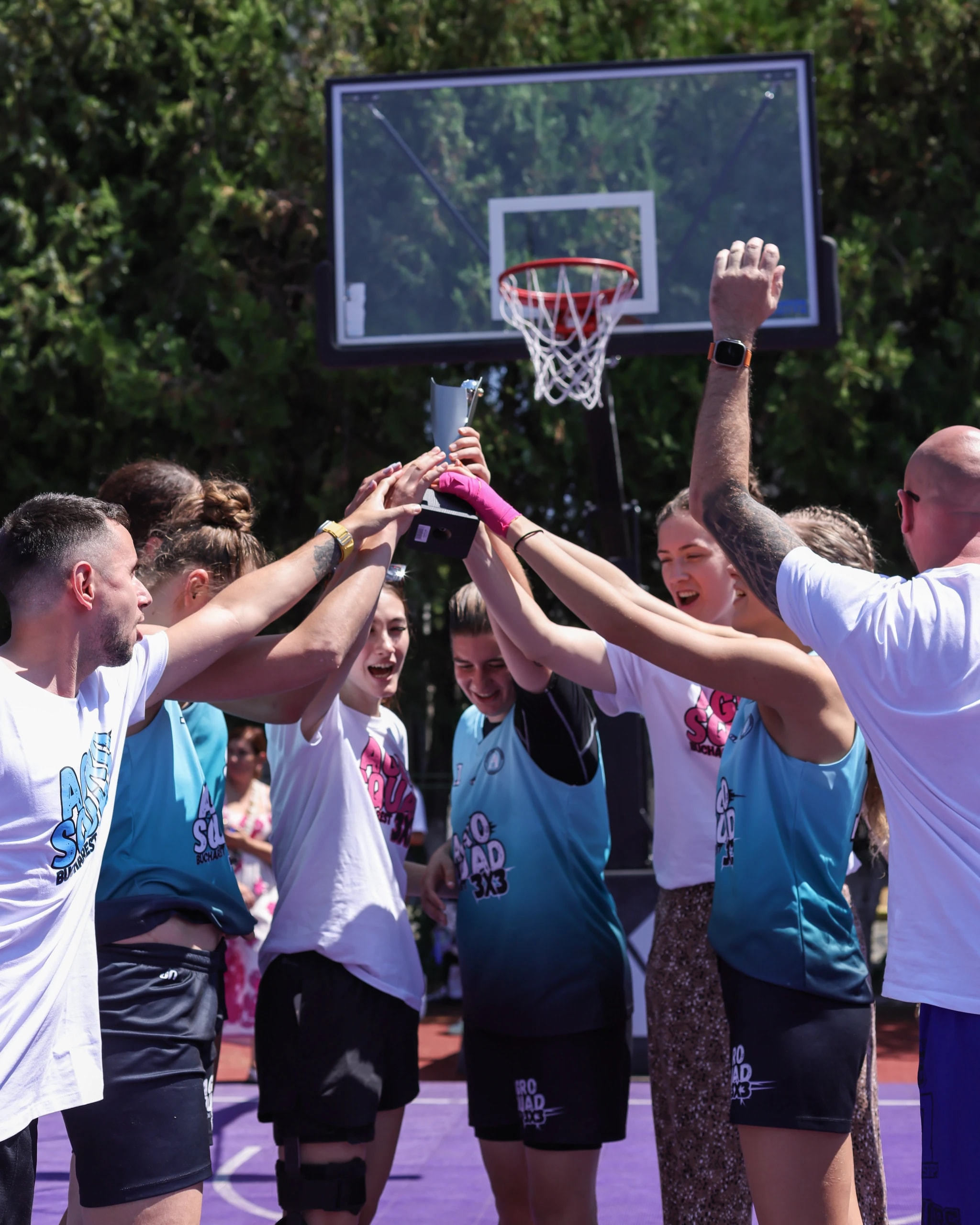 Echipa de 3x3 ridicând împreună trofeul, pe terenul din aer liber
