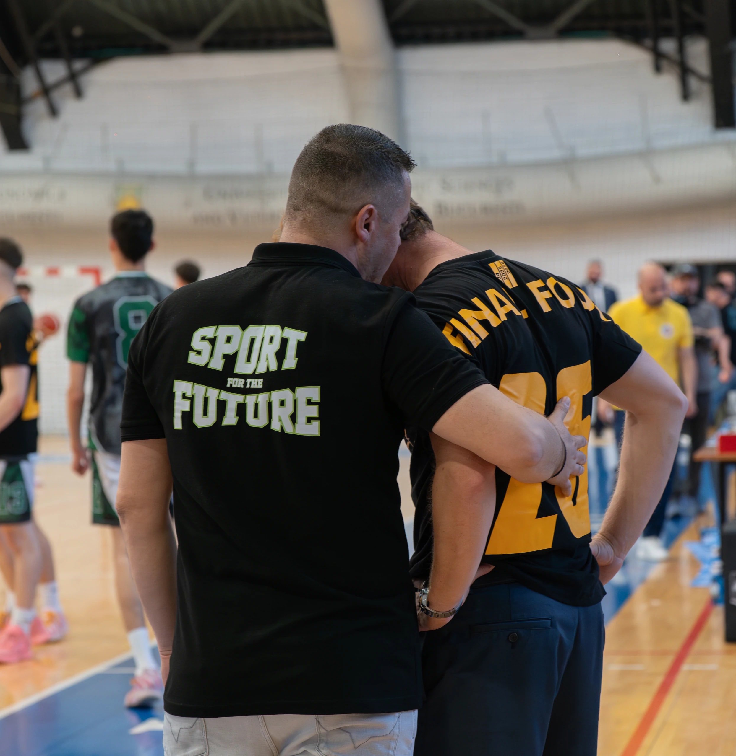 Doi oameni ai clubului, pe marginea terenului, la un turneu Final Four