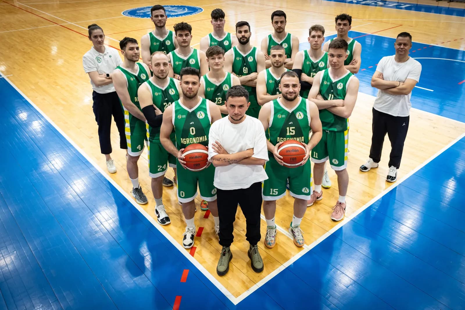 Echipa masculină de baschet și staful, aliniați pe teren pentru fotografia de echipă