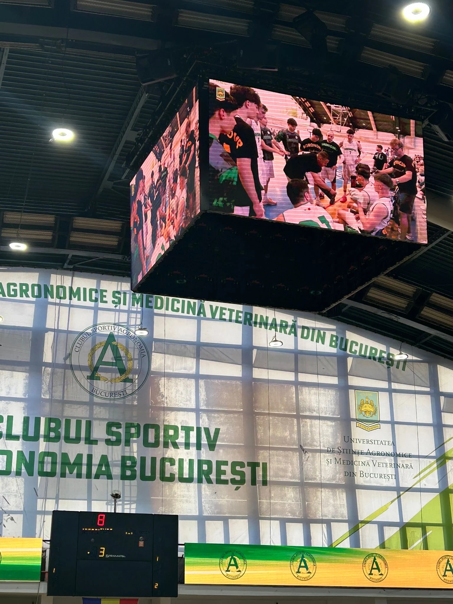 Tabela de marcaj tip cub, suspendată deasupra terenului, cu bannerul Clubului Sportiv Agronomia București pe perete